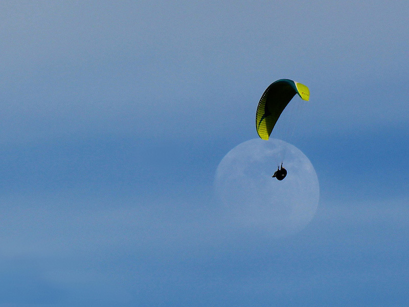 Paraglider silhouetted against the Moon