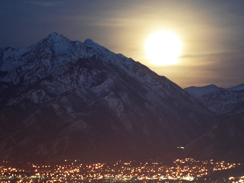Moonrise over a tall mountain with city lights in the foreground