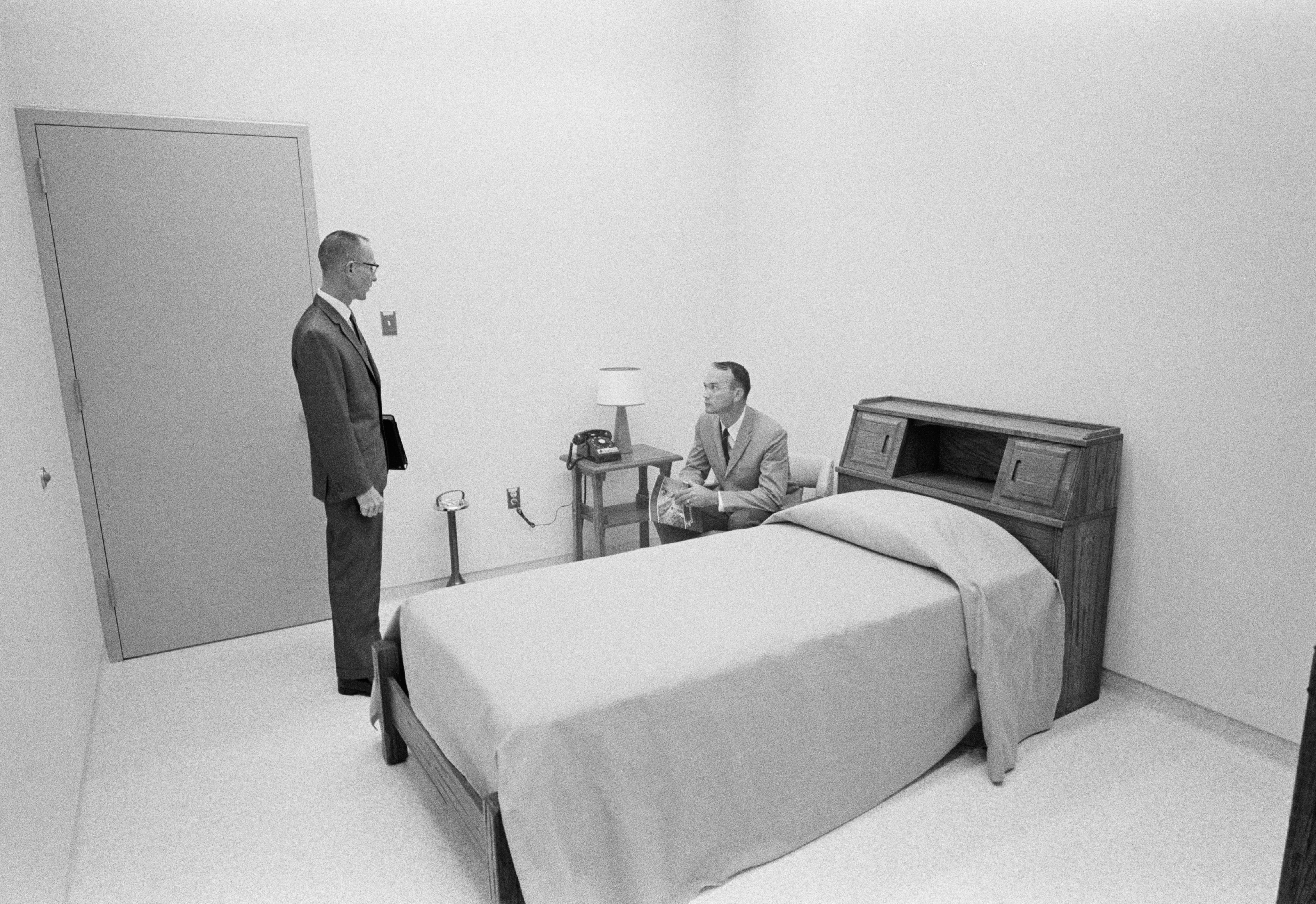 Black and white image of two men in sterile bedroom.