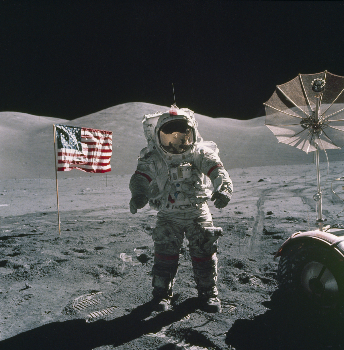 astronaut standing on the lunar surface by flag and rover