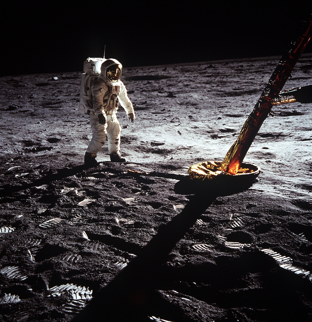 astronaut on the surface of the Moon, next to a lander leg of the lunar module