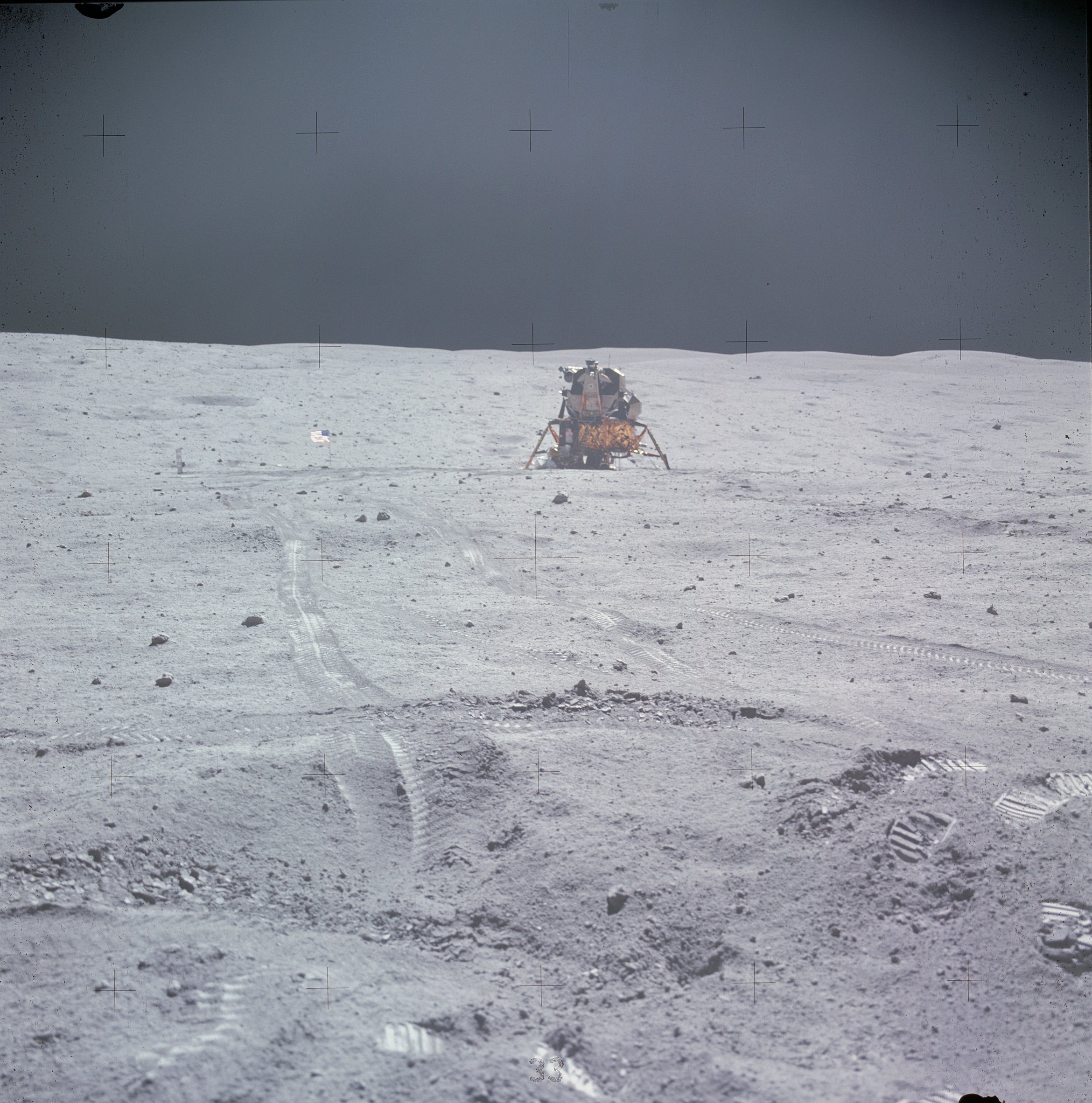 spacecraft in the distance on the gray, sunlit lunar surface