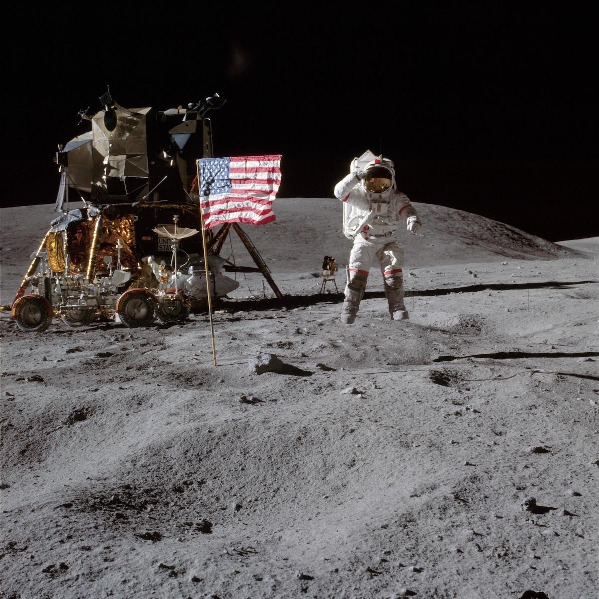 astronaut jumps and salutes near flag and lunar moduel