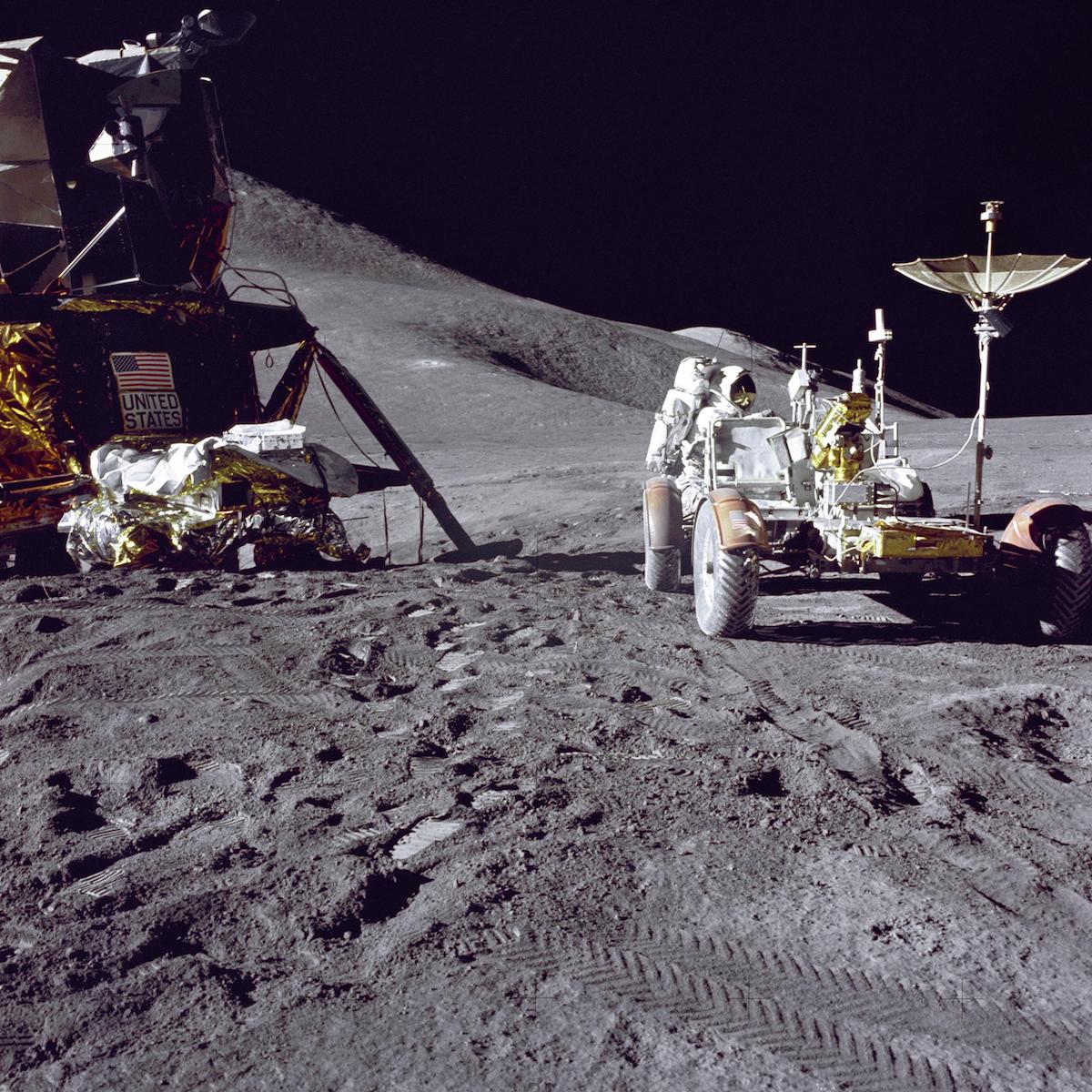 astronaut loading gear into lunar rover near lunar module