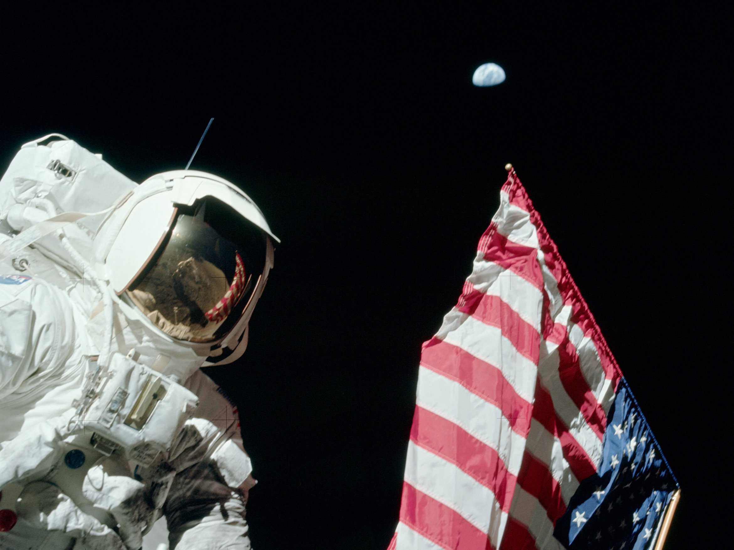 Apollo 17 astronaut Jack Schmitt with the U.S. flag and the Earth in the sky. 