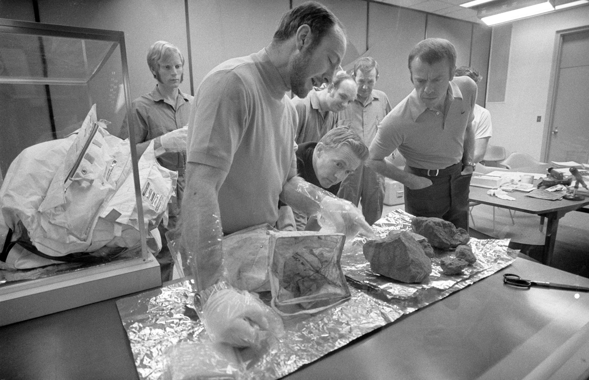 Group of men examining moon rocks