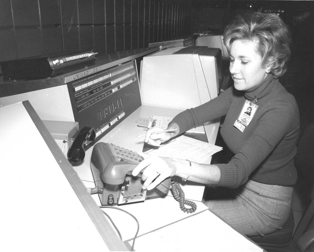 Woman sitting at desk holding telephone and pencil