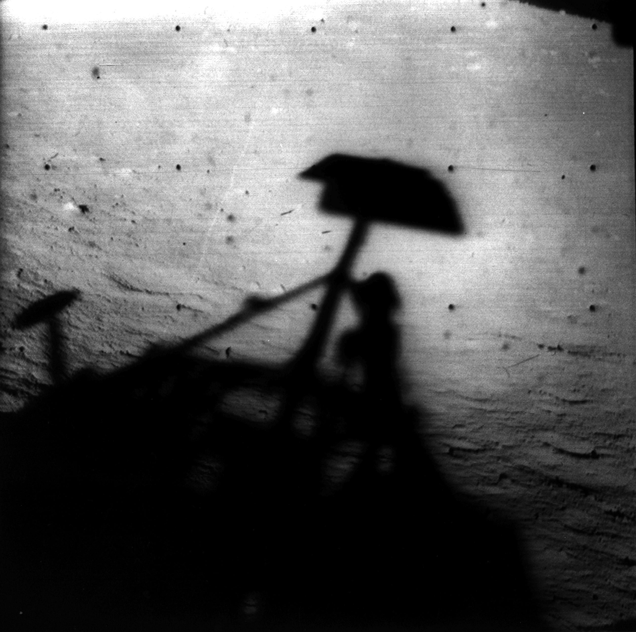 Black and white image of shadow of spacecraft on the surface of the Moon.