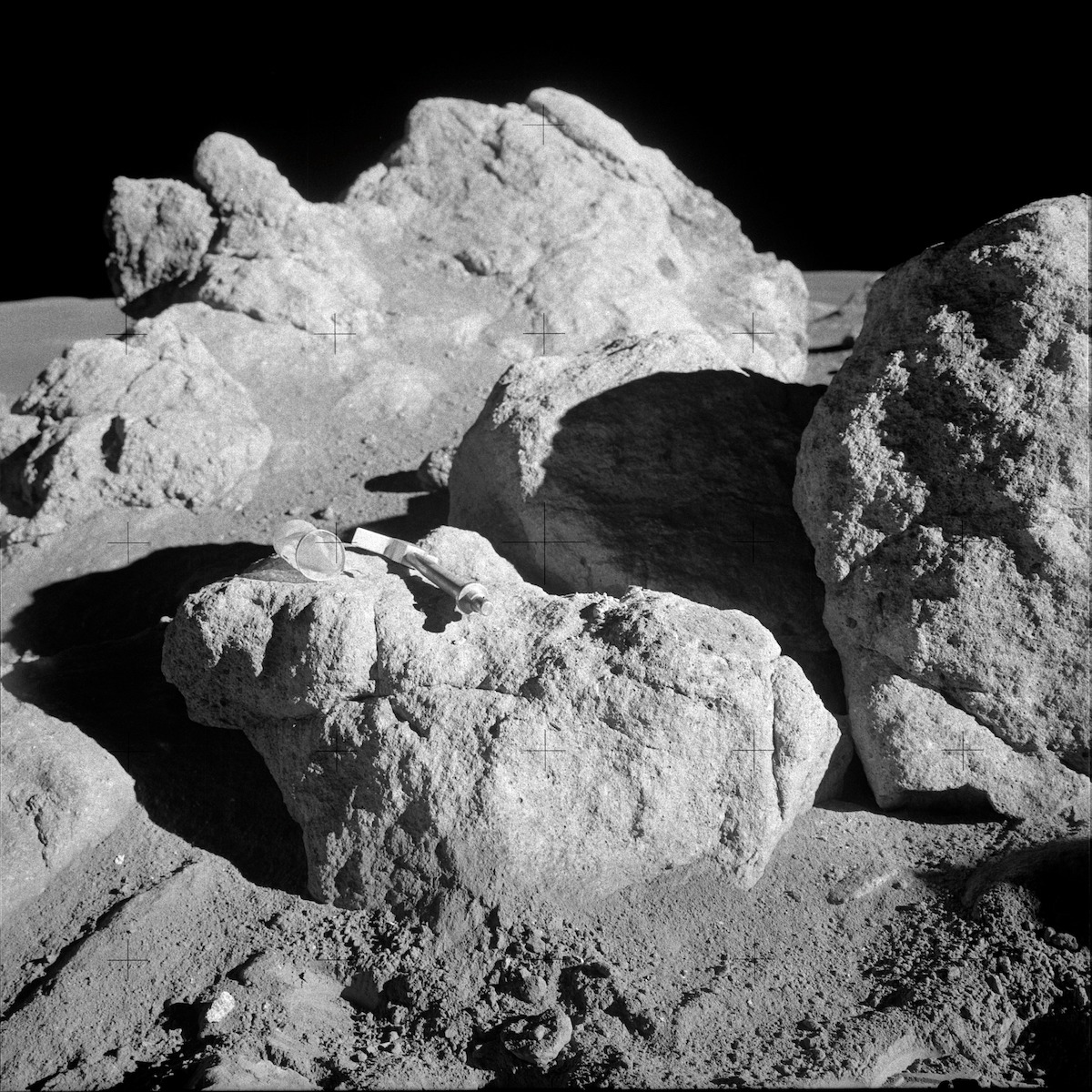 large, white, broken boulder with geologist hammer