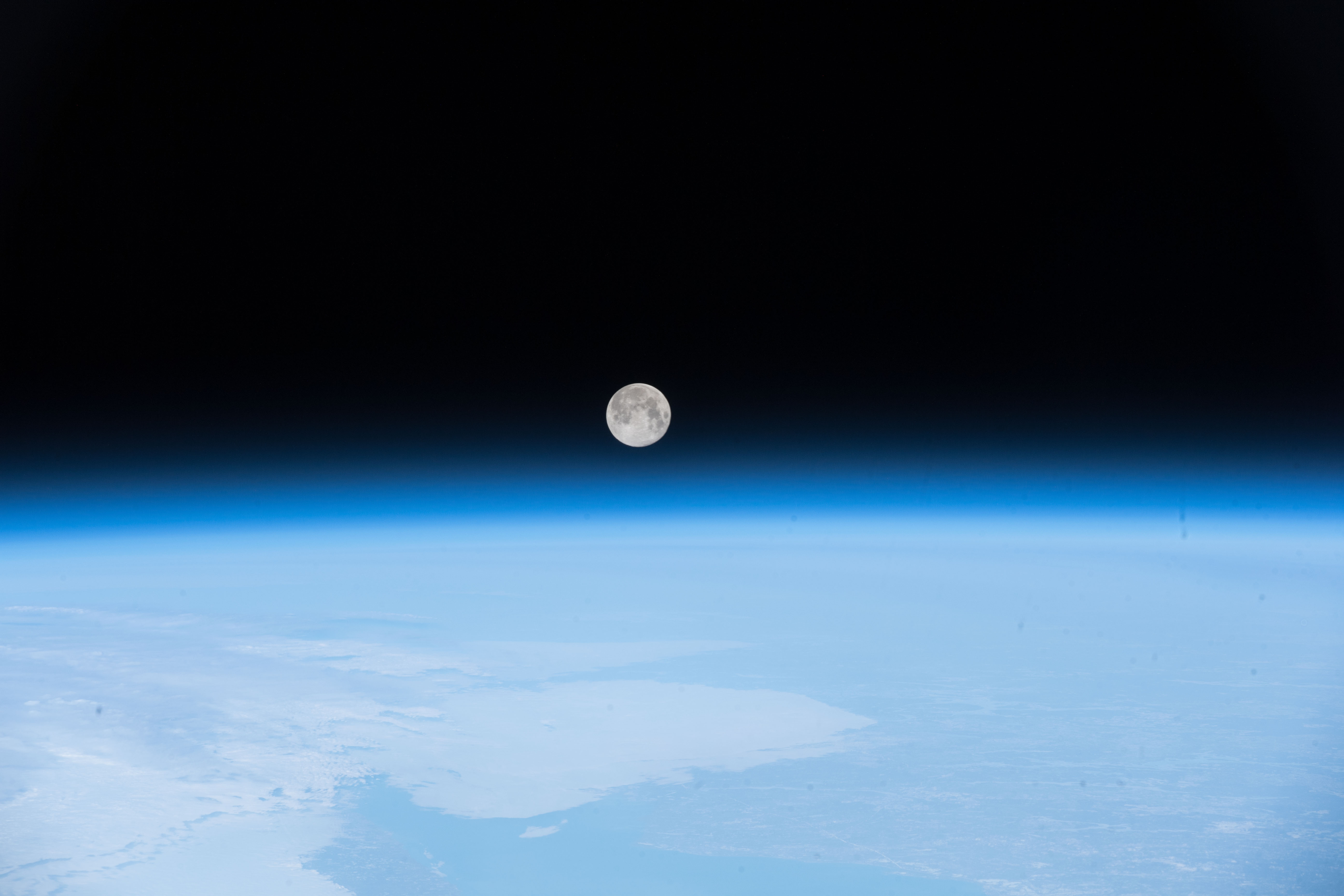 full moon rising over blue atmosphere and ocean