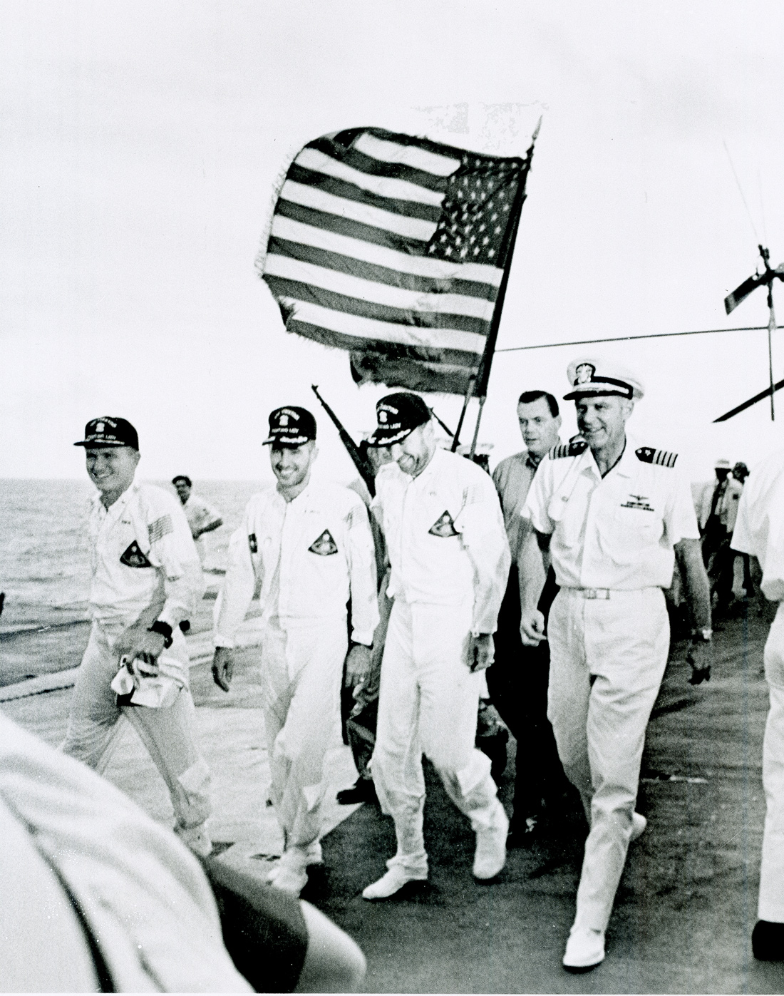 Group of men walking with American flag flying behind them