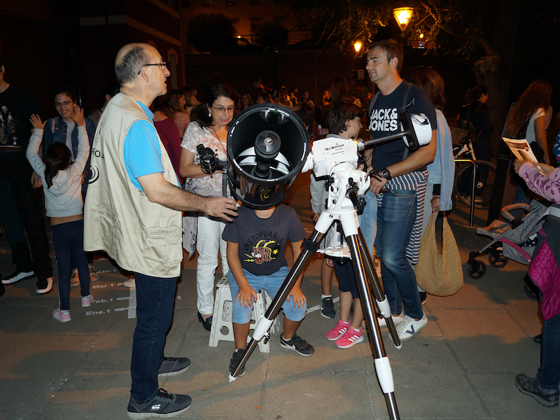 Group of people using a large telescope at night