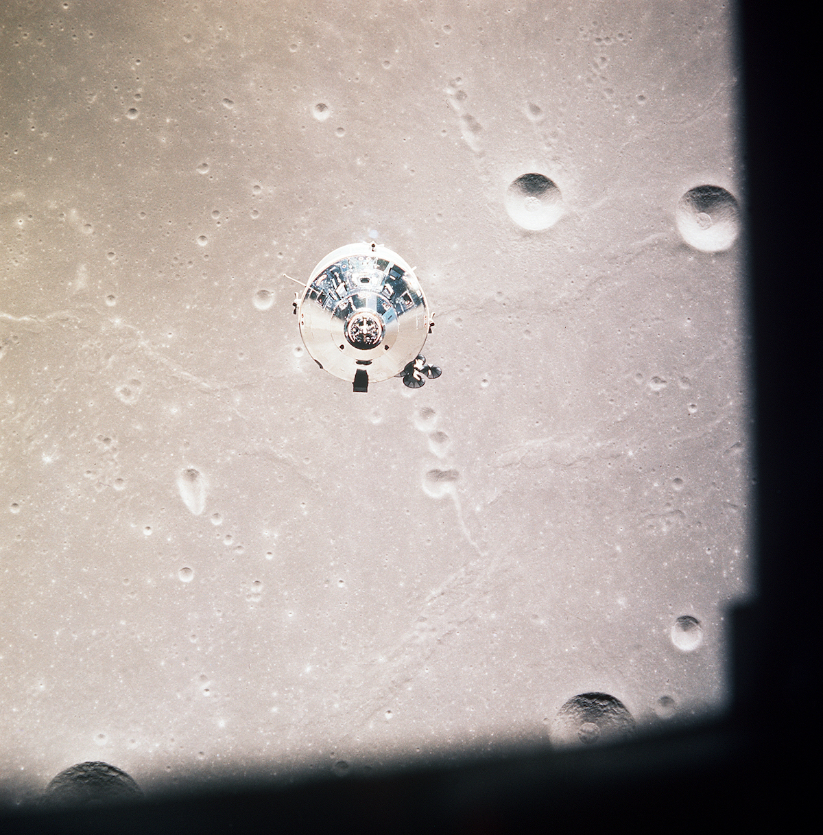 reflective metal spacecraft above the cratered lunar surface
