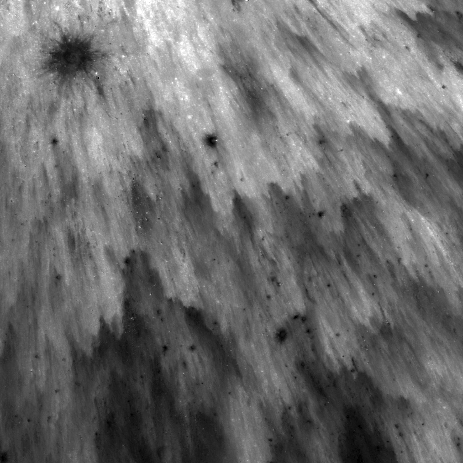 Black and white image showing a spray of impact debris from a moon crater.